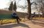 Elderly Man Sitting On A Bench Near His Bicycle In A City Park