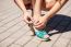 Female Hands Buttoning Shoe On The Sidewalk