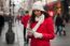 Woman In Red Coat And Wool Cap And Gloves With Smartphone In Han