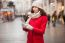 Woman In Red Coat And Wool Cap And Gloves With Smartphone In Han