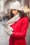 Woman In Red Coat And Wool Cap And Gloves With Smartphone In Han