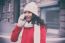 Woman In Red Coat And Wool Cap And Gloves With Smartphone In Han