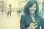 Young Woman With Smile And Smartphone Walking On Street