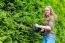 Young Dutch Woman Holding Hedge Trimmer At Conifers