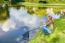 Young Dutch Woman At Waterside With Fishing Rod And Net