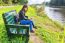 Woman Operating Mobile Phone On Bench At River