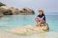 Boy With Hat Sitting On Rock In Sea