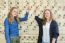 Two Female Students Pointing At Periodic Table In Chemistry Less