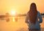 Silhouette Of Relaxing Young Woman On Wooden Pier At The Lake In Sunset