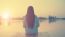 Silhouette Of Relaxing Young Woman On Wooden Pier At The Lake In Sunset