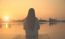 Silhouette Of Relaxing Young Woman On Wooden Pier At The Lake In Sunset