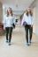 Two Dutch Teenage Girls Walking In Long School Corridor Carrying