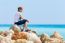 Dutch Woman Sitting On Rocks With Blue Sea Horizon