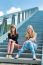 Two Dutch Girls Sitting On Metal Bridge