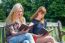 Two Girls Reading Books On Bench In Nature