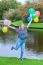 Girl Holding Up Many  Coloured Balloons At Pond