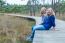 Two Sisters Sitting On Wooden Path In Forest