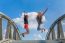 Two Happy Teenage Girls Jumping On Bridge