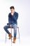 Male Model In Denim Jeans Sitting On A Chair . Studio Shoot