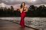 Beautiful Young Woman In The Gardens Wearing A Long Silk Red Dress