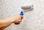 Man's Hand Smoothing The Wallpaper With A Roller Closeup