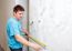 Man Measuring The Wall With A Tape Measure