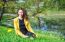 Young Woman Sitting On The Grass Near The Pond