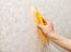 Man's Hand Smoothing The Wallpaper With A Spatula