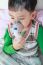 Asian Child Holds A Mask Vapor Inhaler For Treatment Of Asthma In Hospital