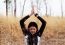 Asian Woman Meditating In Grass Field 