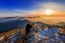 Professional Photographer Takes Photos With Camera On Tripod On Rocky Peak At Sunset