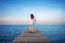 Woman Walking On Wooden Bridge Extended Into The Sea