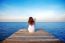 Girl Sitting Alone And Hand Holding Camera On A The Wooden Bridge On The Sea