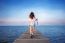 Woman Walking On Wooden Bridge Extended Into The Sea