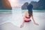 Young Woman In Red Bikini Sitting On The Beach