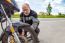 Elderly Man Checks His Motorcycle's Wheel