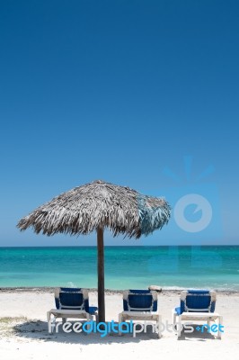 3 Deck Chairs On White Sunny Beach Under Umrella Stock Photo