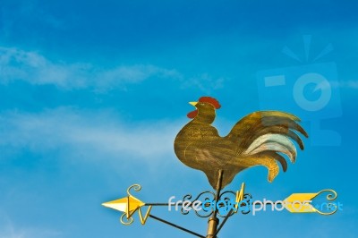 A Cockerel Wind Vane Against Blue Sky Stock Photo