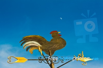 A Cockerel Wind Vane Against Blue Sky Stock Photo