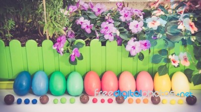 A Few Colorful Easter Eggs At The Green Garden With Colorful Purple  And Pink Flowers And Candies And Chocolate Happy Easter Straight View Stock Photo