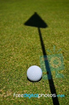 A Golf Ball And The Shadow Of The Hole Flag Stock Photo