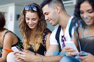 A Group Of Students Having Fun With Smartphones After Class Stock Photo