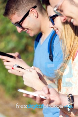 A Group Of Students Having Fun With Smartphones After Class Stock Photo