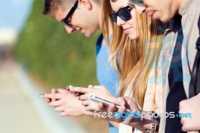 A Group Of Students Having Fun With Smartphones After Class Stock Photo