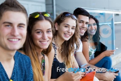 A Group Of Students Having Fun With Smartphones After Class Stock Photo