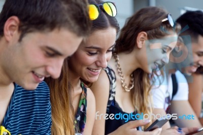 A Group Of Students Having Fun With Smartphones After Class Stock Photo