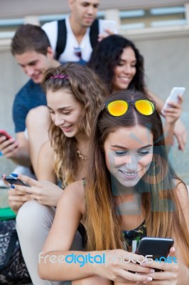 A Group Of Students Having Fun With Smartphones After Class Stock Photo