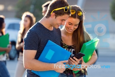 A Group Of Students Having Fun With Smartphones After Class Stock Photo