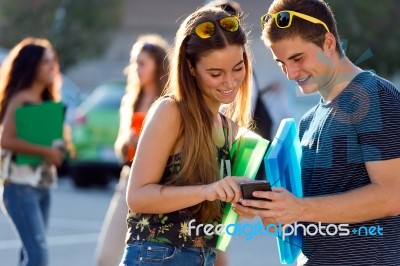 A Group Of Students Having Fun With Smartphones After Class Stock Photo