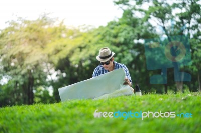 A Happy Traveller Mid Aged Man Sit Outdoor In Green Park, Lookin… Stock Photo